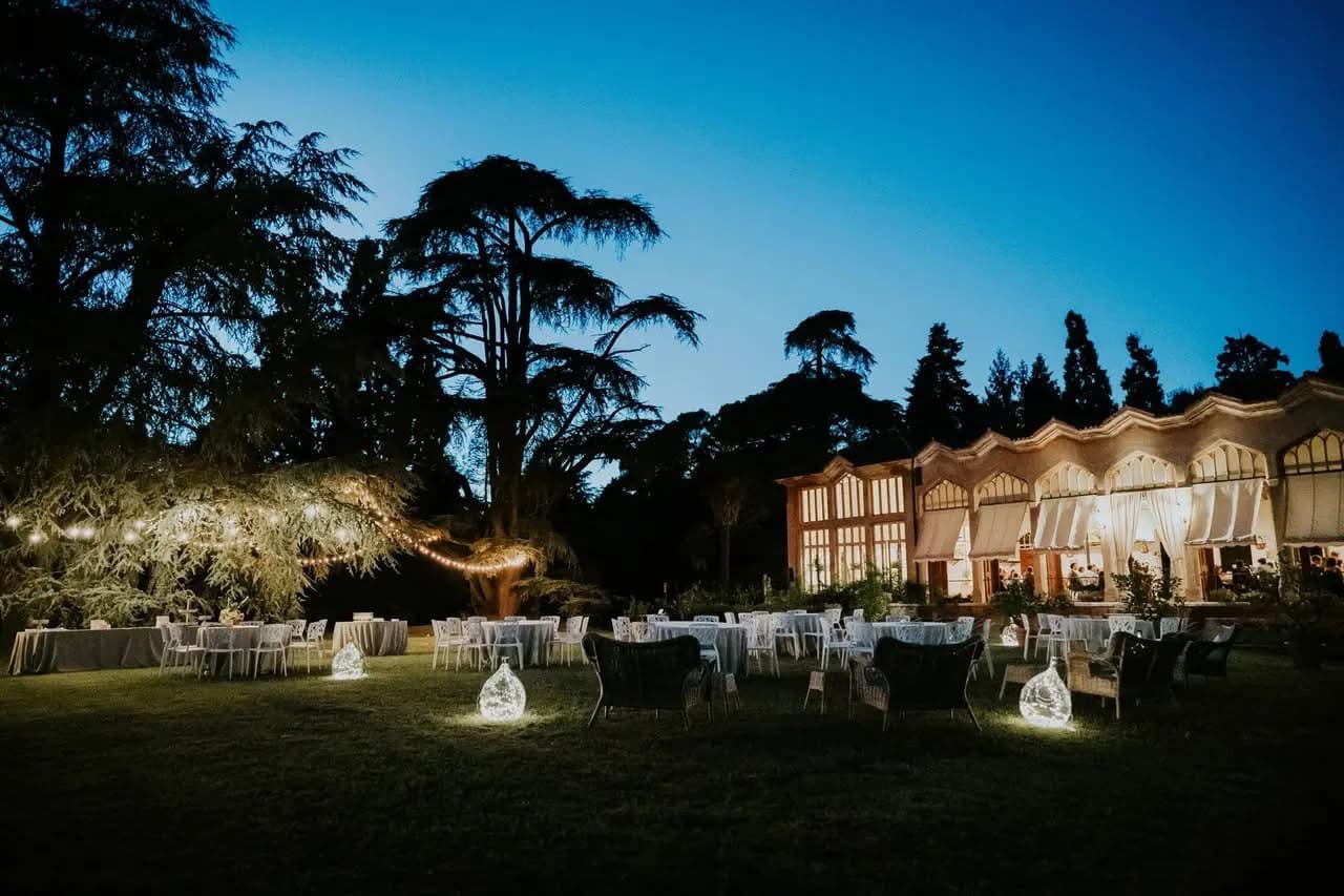 L’Aranciera illuminata al crepuscolo con il parco allestito per un matrimonio