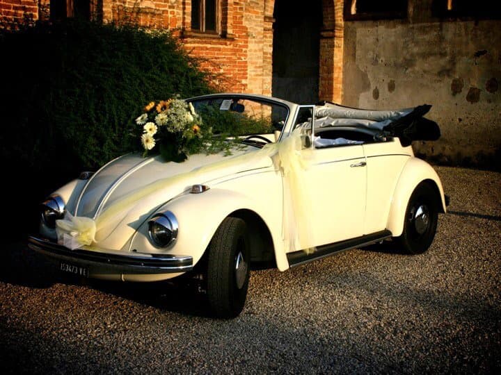 Maggiolino Cabrio del 1966 con bouquet di fiori, parcheggiato accanto a un muro storico